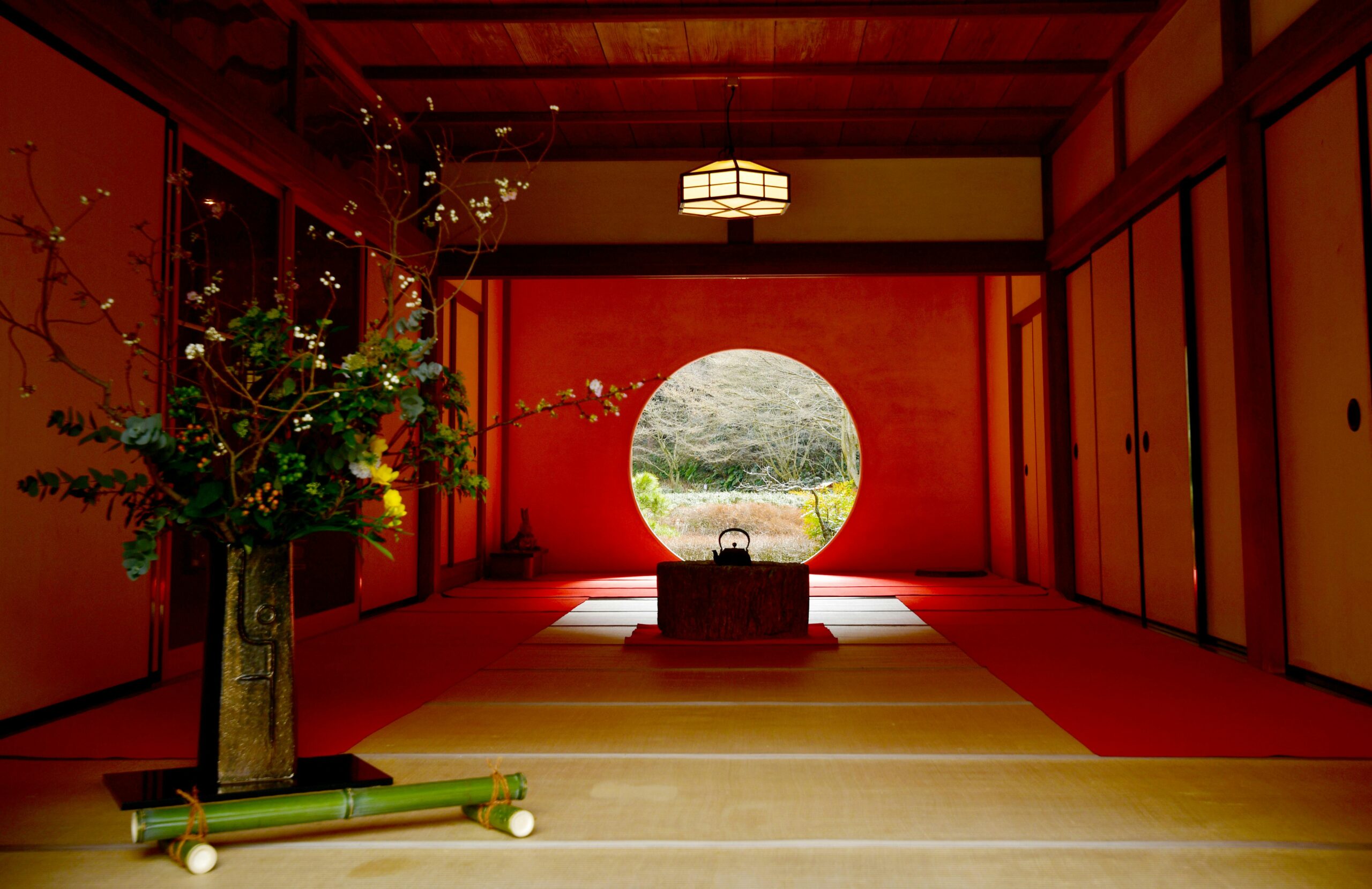 Elegant Japanese teahouse interior featuring a floral arrangement and circular window view.