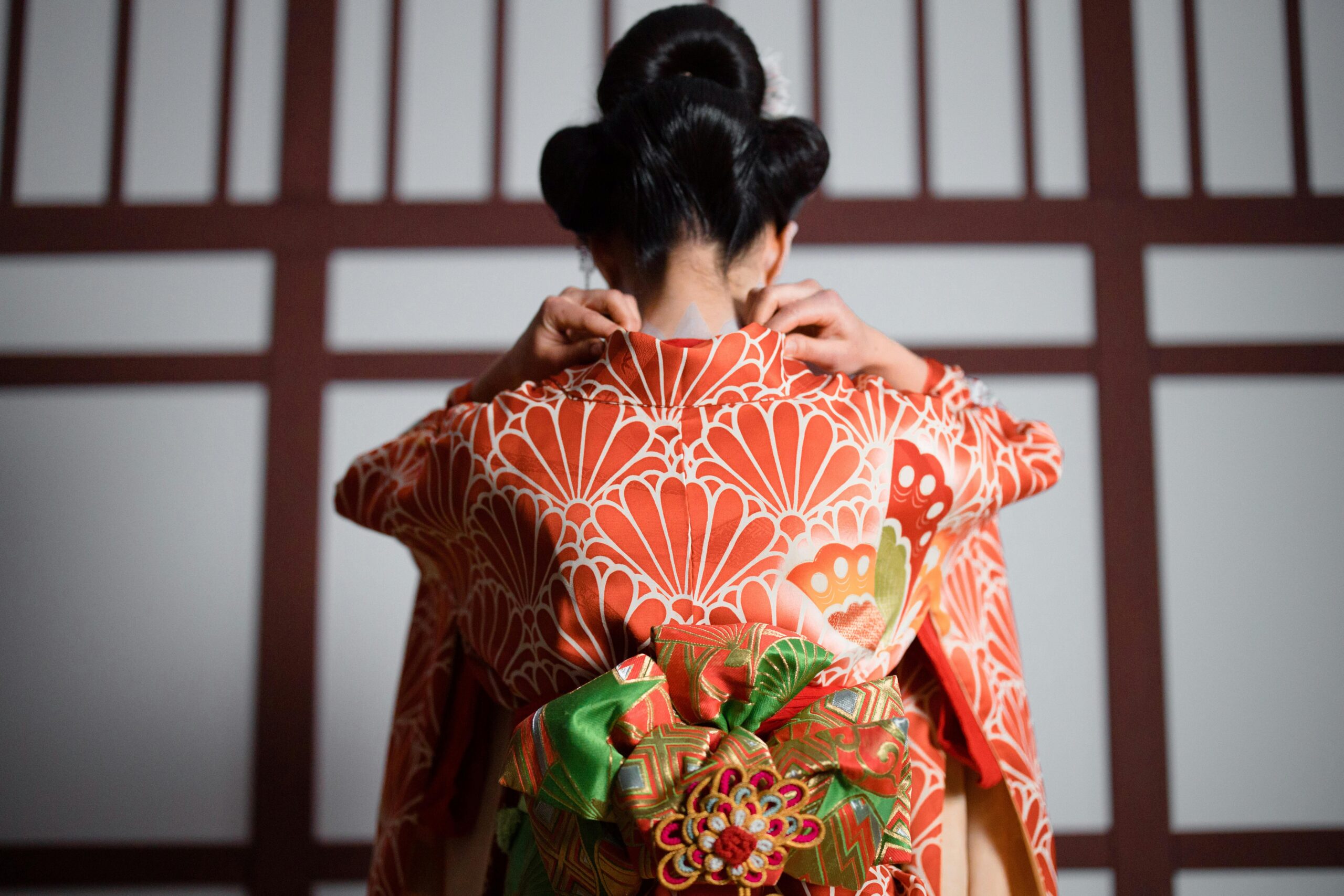 A graceful view of a woman adjusting her kimono, showcasing traditional Japanese aesthetics.