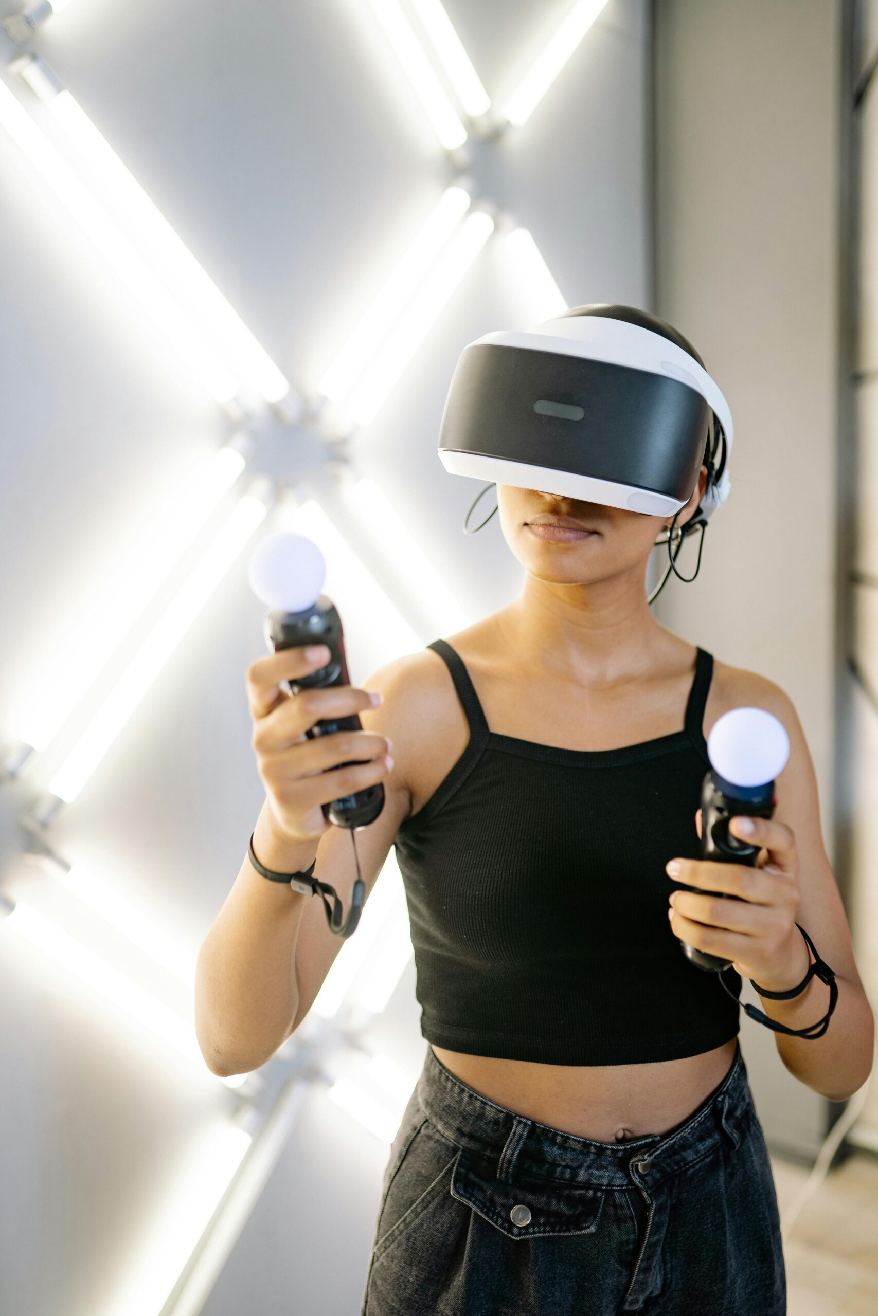 A woman experiencing immersive gaming with VR goggles and controllers in a modern setting.